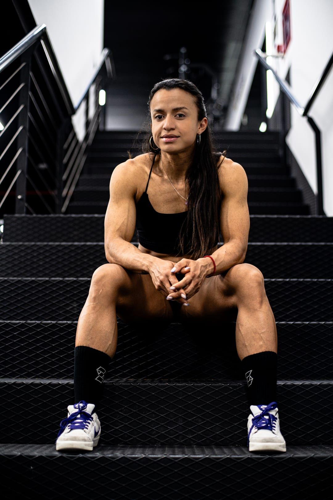 Chery Figueroa sentada en las escaleras del gimnasio, mirando a cámara